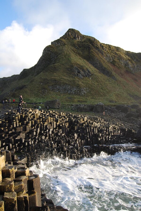 A coastal area with a rocky breakwater and a mountain in the background. - Causeway Lodge (Bushmills)