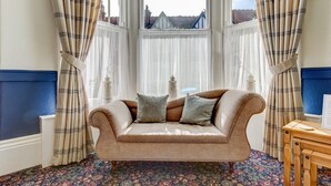 A room with a sofa, a table, and a view through a window. - The Cavendish (Scarborough)
