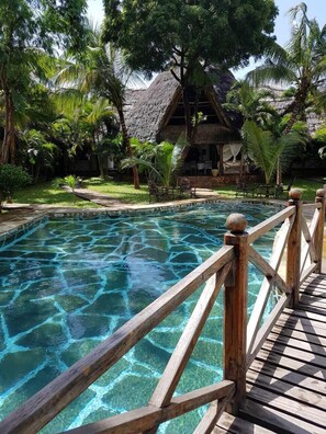 Una piscina al aire libre, sombrillas, sillones reclinables de piscina