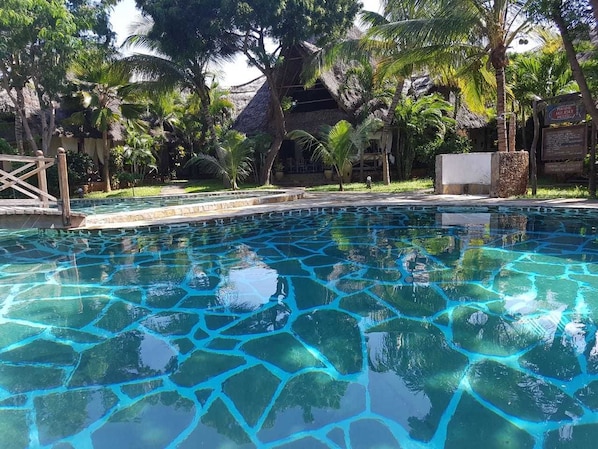 Una piscina al aire libre, sombrillas, tumbonas