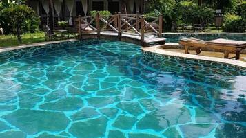 Una piscina al aire libre, sombrillas, sillones reclinables de piscina