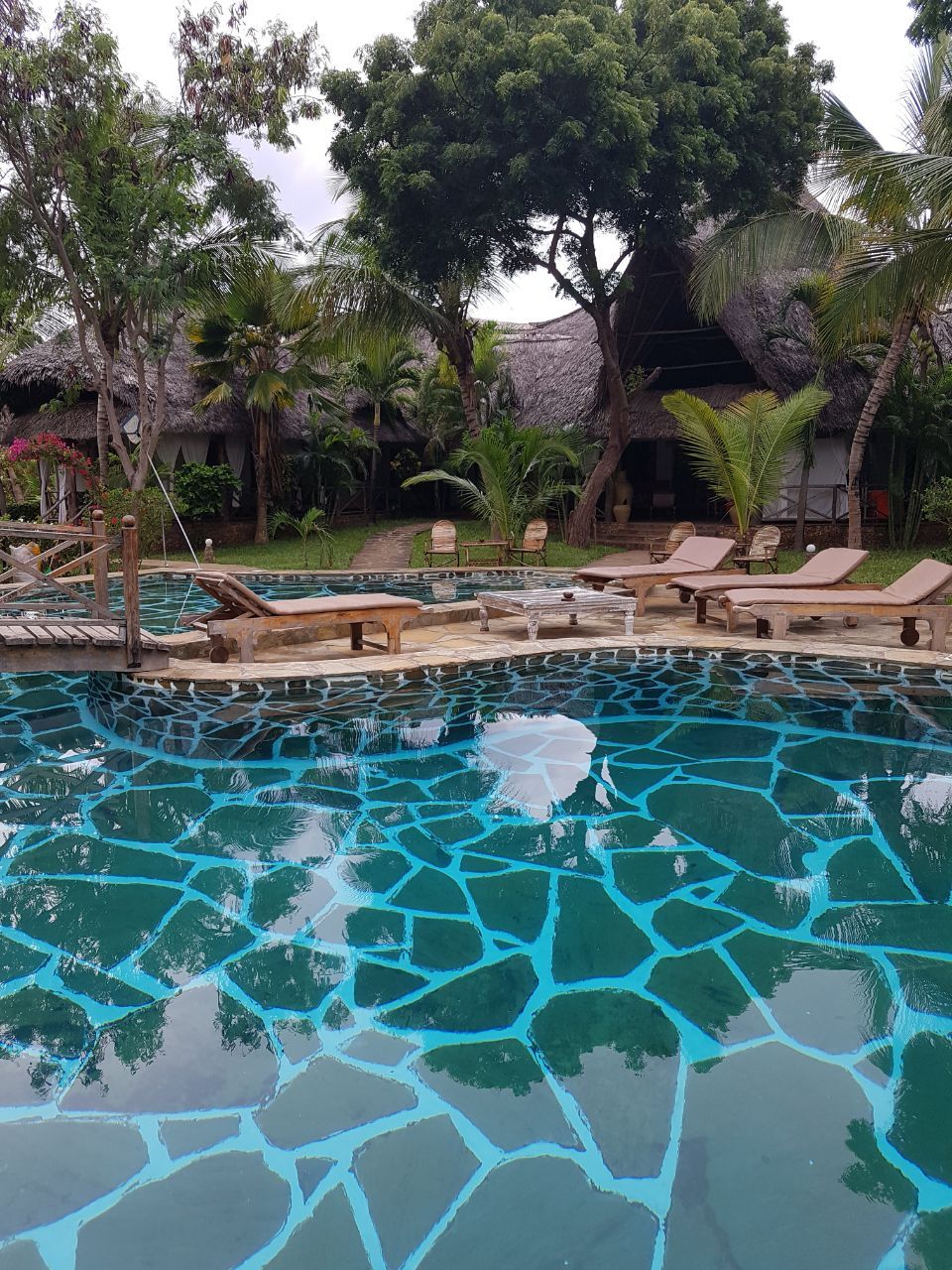 A swimming pool with lounge chairs and a wooden deck.