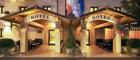 A hotel entrance with two "HOTEL" signs, a brick facade, and potted plants.