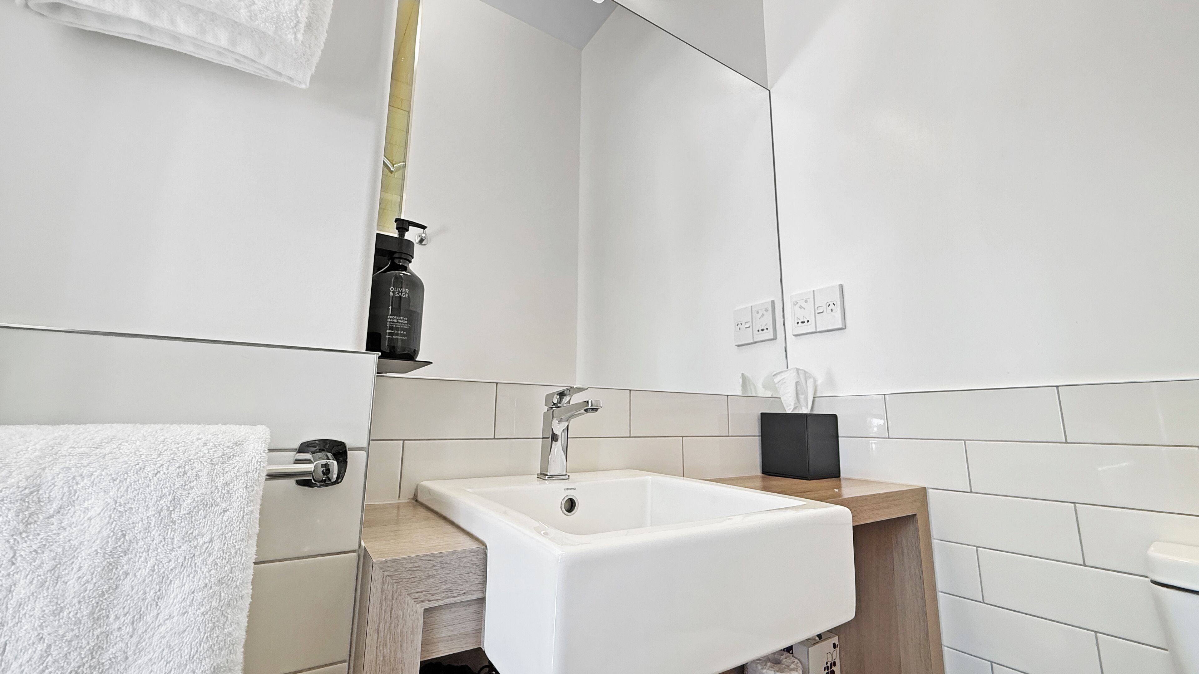A modern bathroom with a white sink, a mirror, and a towel rack.