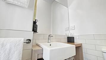A modern bathroom with a white sink, a mirror, and a towel rack.