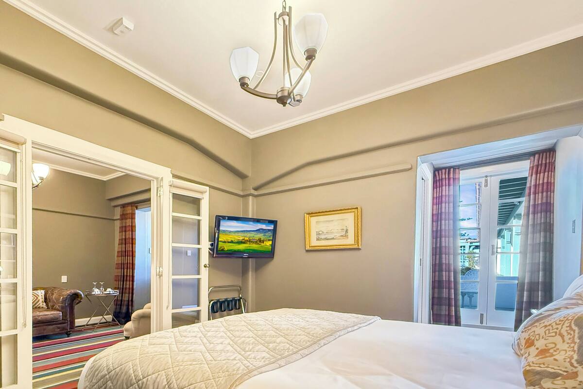 A hotel room with a bed, a television, a wardrobe, and a window with curtains.