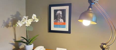A desk with a framed picture, a desk lamp, a potted plant, a telephone, and a business card.