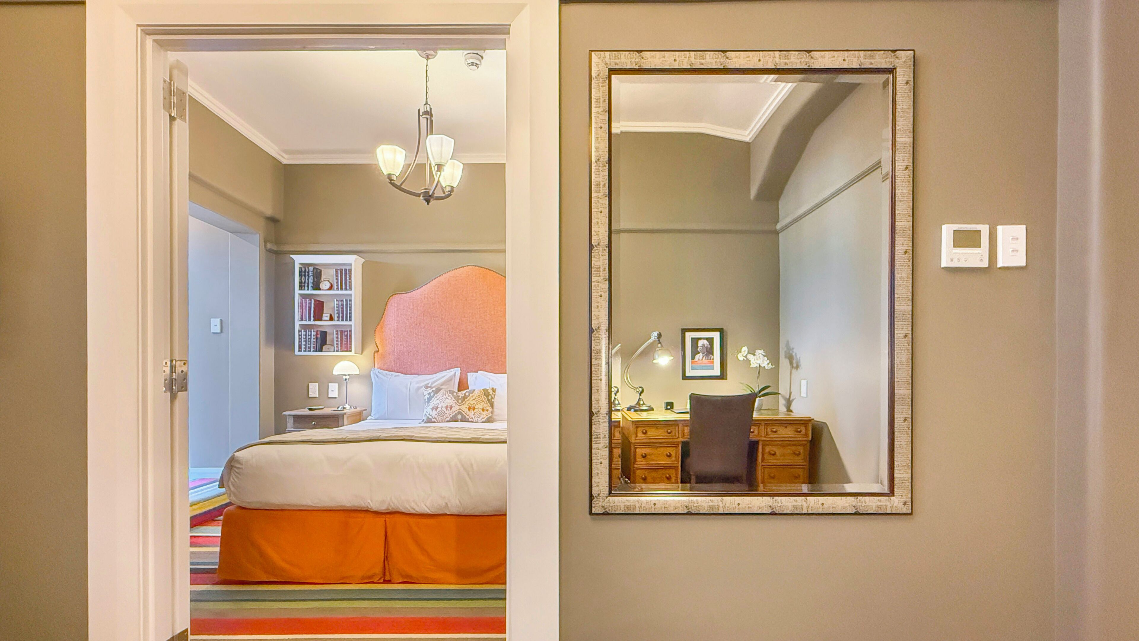 A bedroom with a bed, a dresser, a mirror, and a bookshelf.