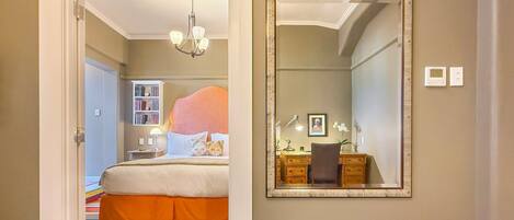 A bedroom with a bed, a dresser, a mirror, and a bookshelf.