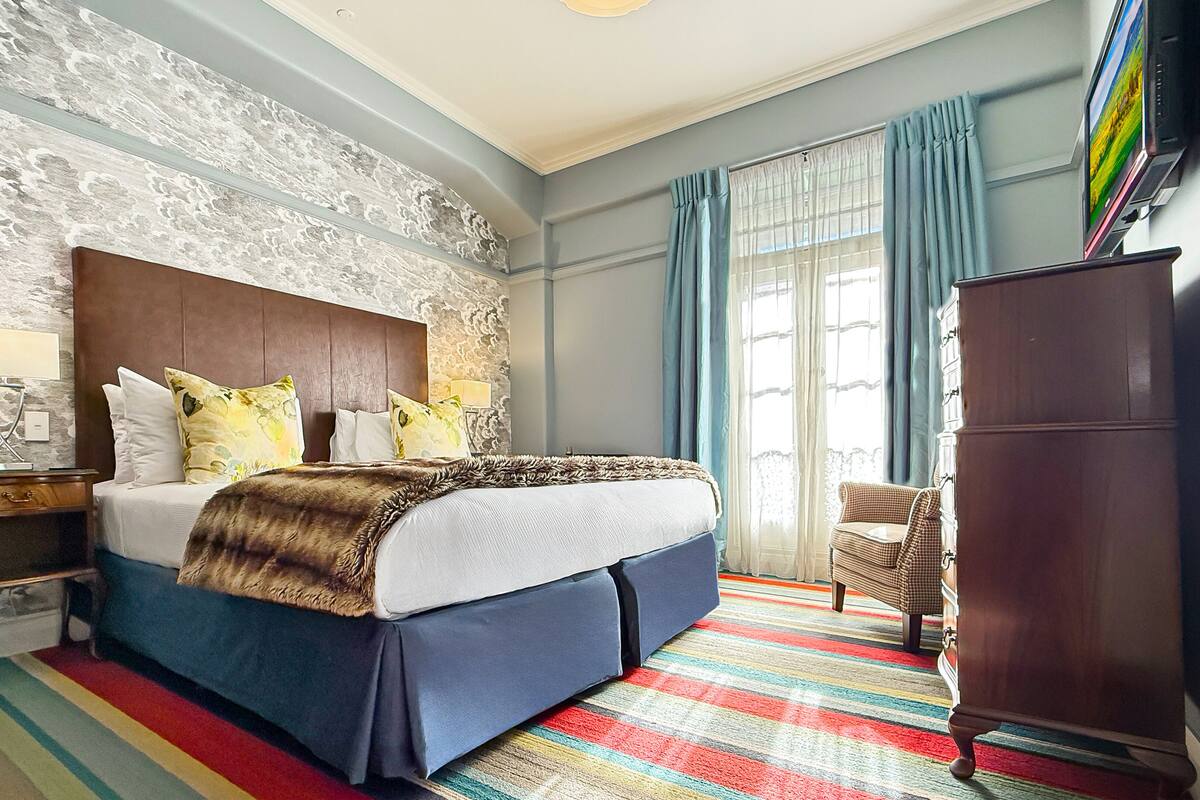 A bedroom with a bed, nightstand, lamp, and a wardrobe.