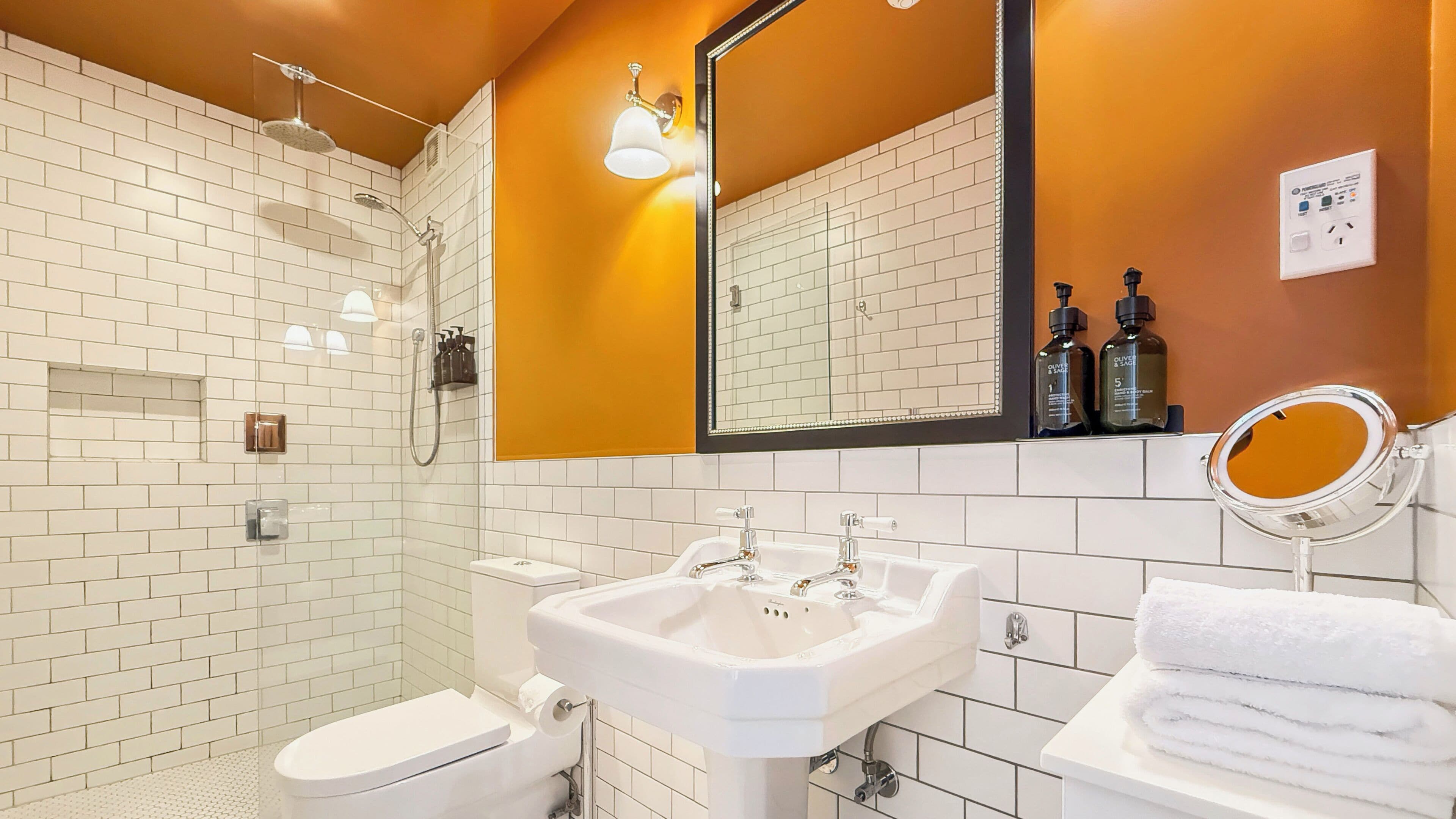 A bathroom with a white toilet, a sink, a shower, and a mirror.
