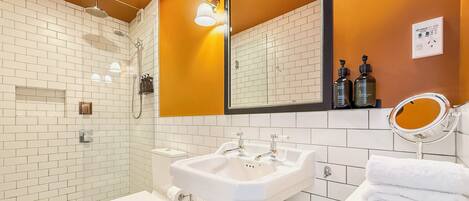 A bathroom with a white toilet, a sink, a shower, and a mirror.