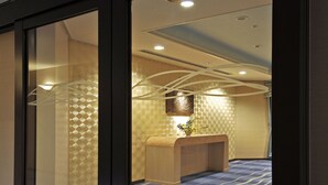 A reception area with a reception desk, patterned wallpaper, and a blue carpet. - Rihga Royal Hotel Niihama (Niihama)