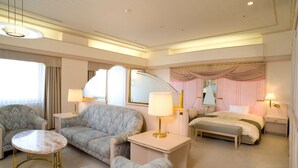 A hotel room with a bed, two armchairs, a small table, and a bedside table with lamps. - Rihga Royal Hotel Niihama (Niihama)