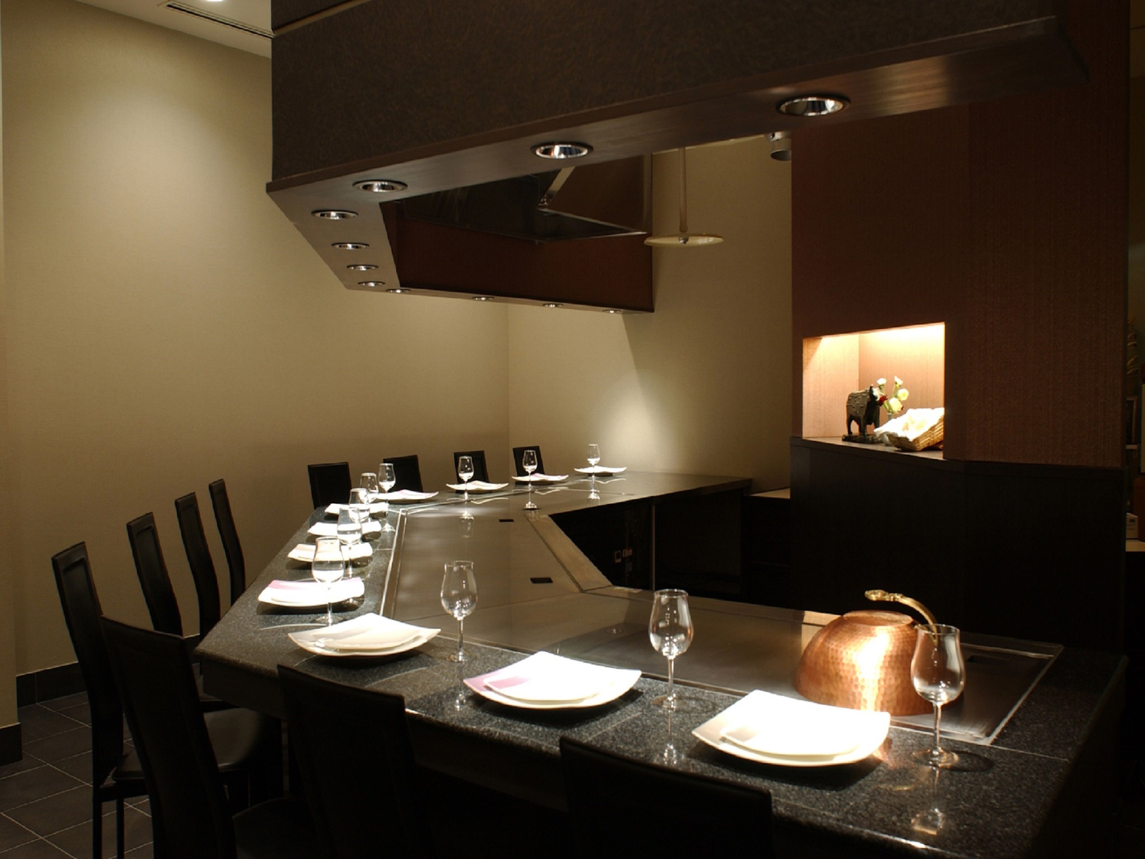 A dining area with a long table set for a meal, chairs, and a modern ceiling design.