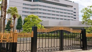 The exterior of the RIHGA ROYAL HOTEL with a modern architectural design, featuring a prominent entrance gate and a series of palm trees in the foreground. - Rihga Royal Hotel Niihama (Niihama)