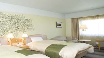 A hotel room with two beds, a small table, a chair, a lamp, and a wall-mounted artwork.