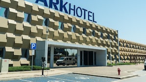 A Park Hotel with a modern facade, a parking area with blue parking lines, and a fire hydrant on the sidewalk.