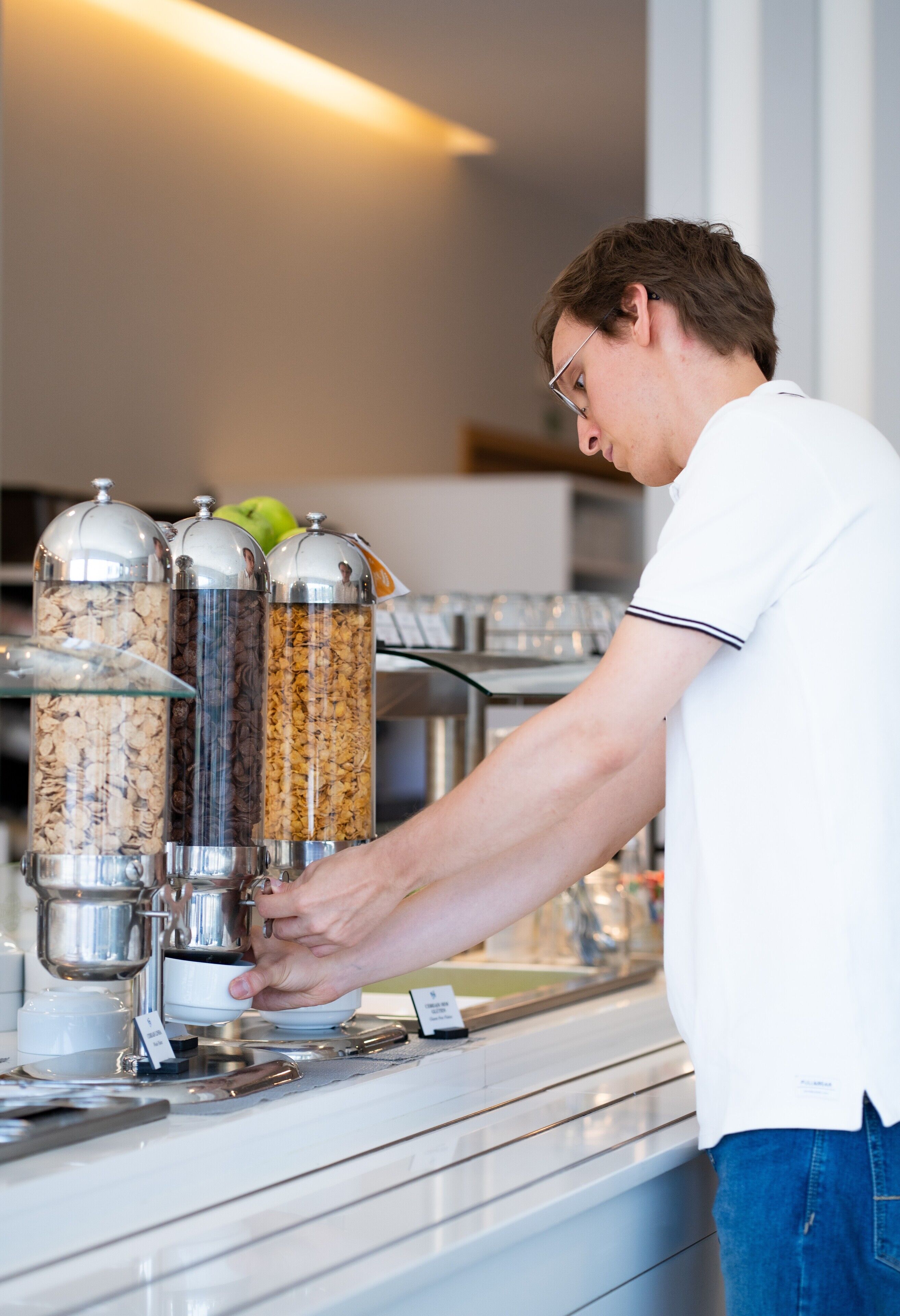 Una persona preparando comida en una estación de buffet con varios recipientes.