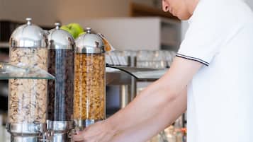 A person preparing food at a buffet station with various food containers.