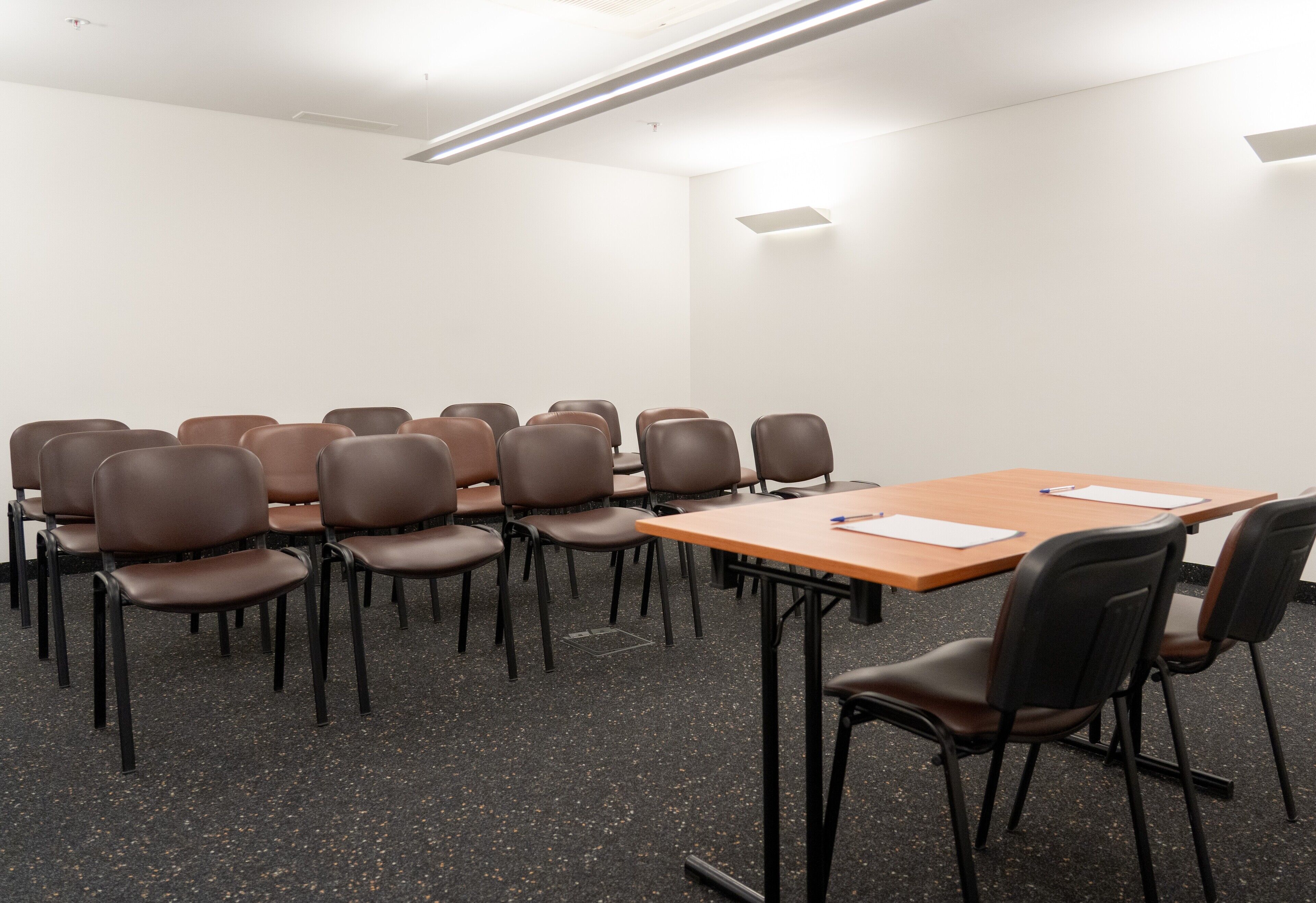 A conference room with a long table, multiple chairs, and a carpeted floor.