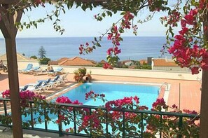 Un espace piscine avec des chaises longues et vue sur la mer.