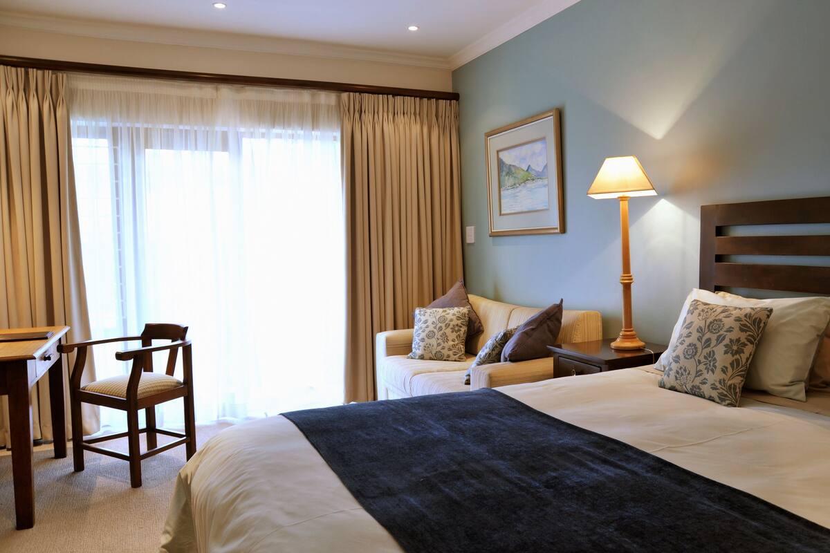 Una habitación de hotel con cama, escritorio, silla y lámpara.