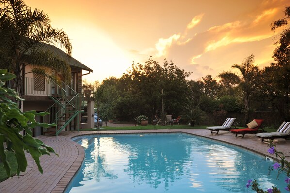 Una piscina al aire libre, sombrillas, sillones reclinables de piscina
