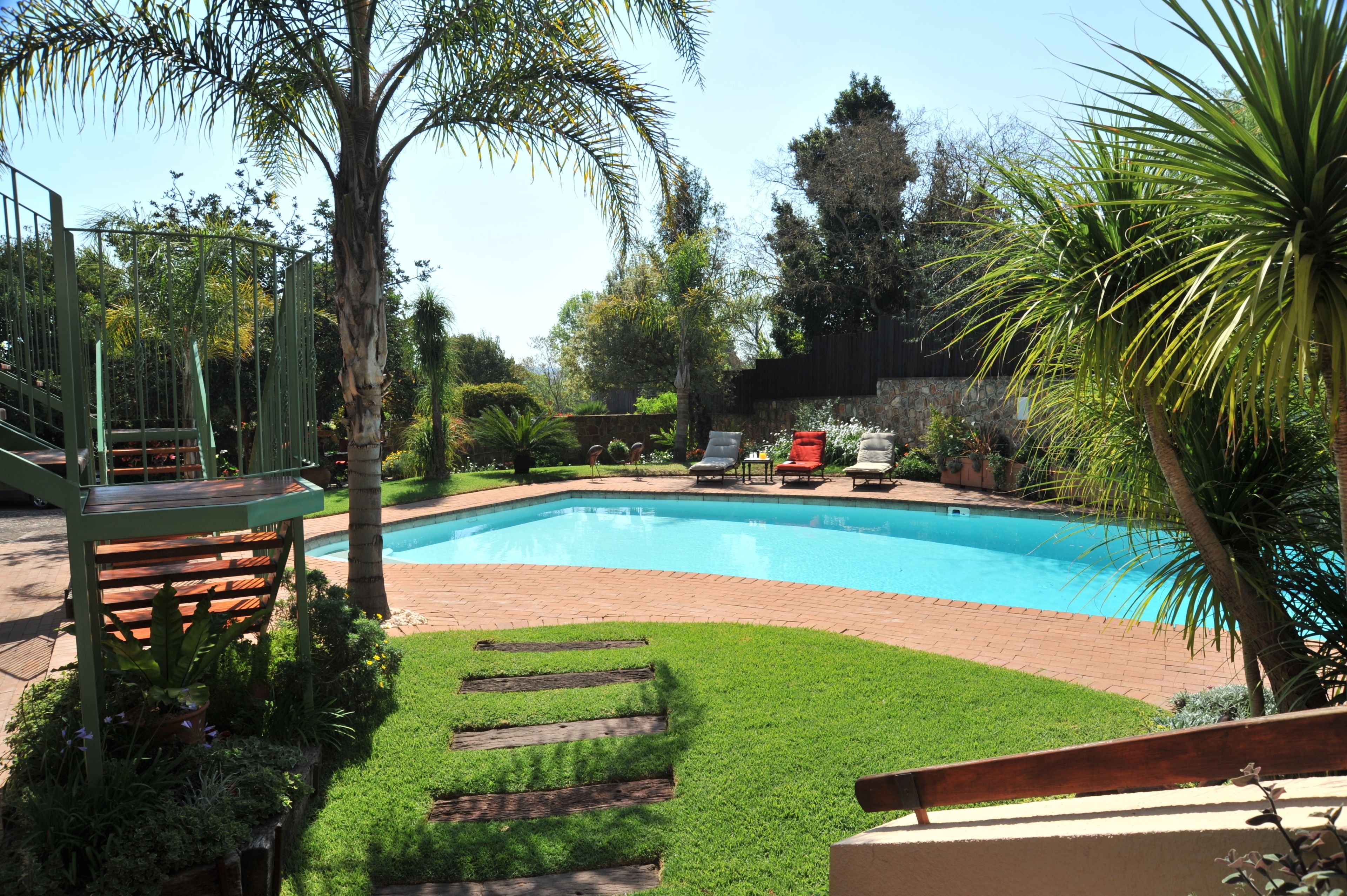 A swimming pool surrounded by a well-maintained lawn and various plants.