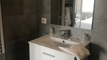 A modern bathroom with a white sink, mirror, and two drawers.