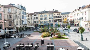 A plaza with outdoor seating and a central garden area. - Hôtel de la Basilique (Epinal)