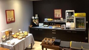 A buffet setup with various food items and a beverage dispenser. - Hôtel de la Basilique (Epinal)
