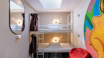 Une chambre avec un lit superposé, une lucarne, un miroir et une fresque murale colorée.