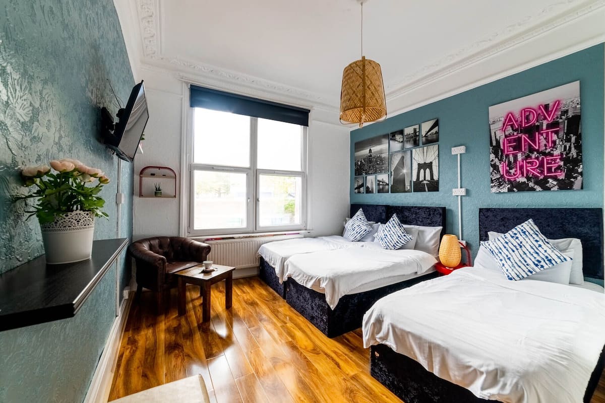 Une chambre d’hôtel avec deux lits, un bureau, une chaise, une plante en pot et une fenêtre donnant sur un beau paysage.