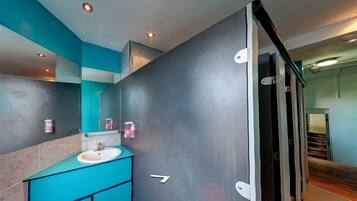 Un baño moderno con tocador verde azulado, lavabo y espejo.