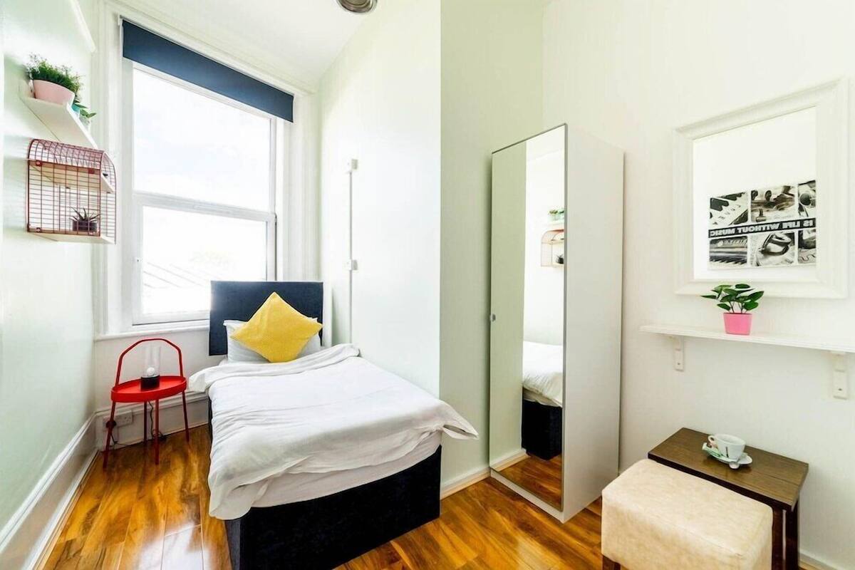 Une chambre à coucher avec un lit, un miroir, une petite table et une fenêtre.