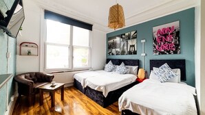 Una habitación con dos camas, un sofá, una mesa y una lámpara colgante.