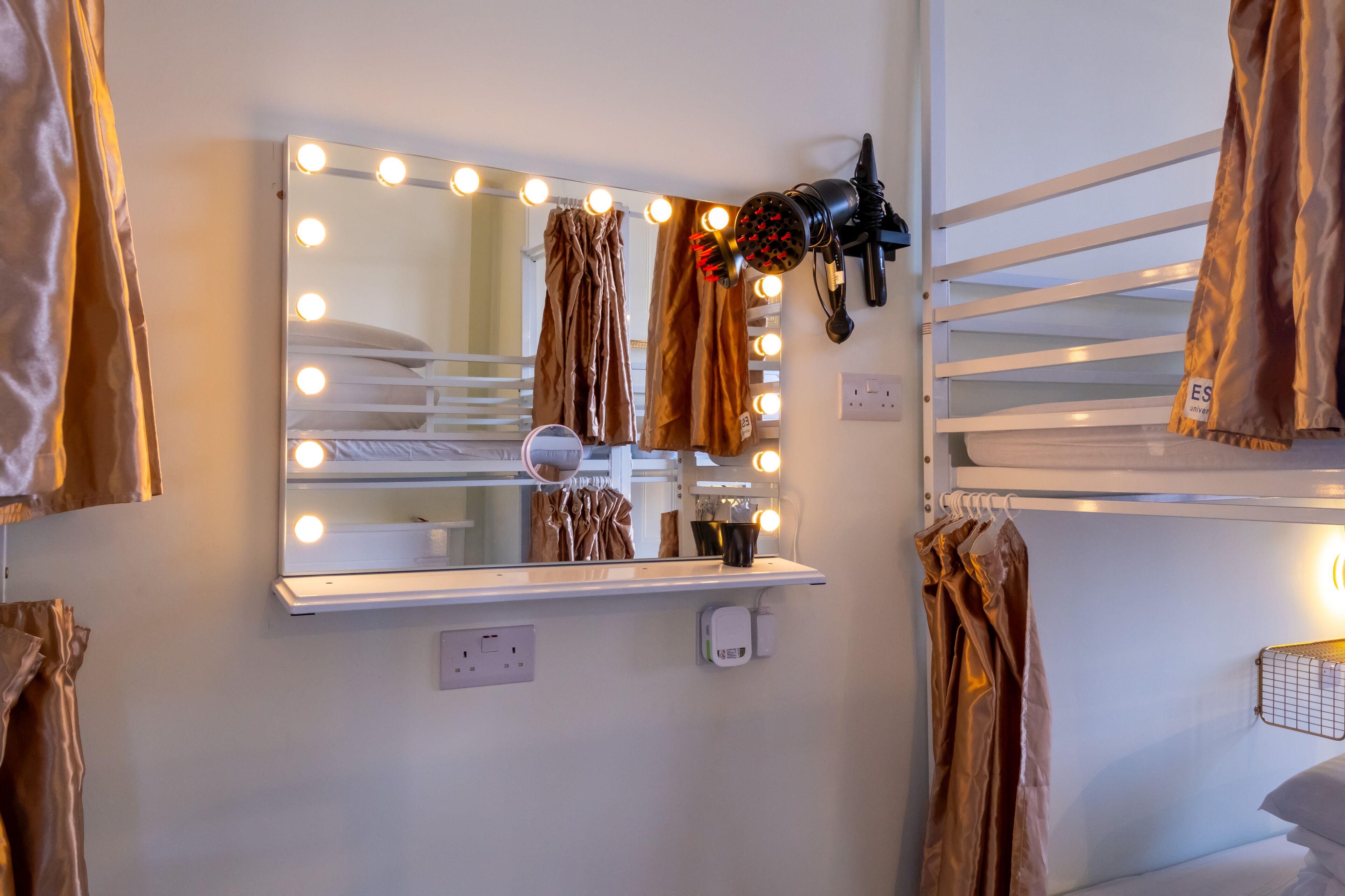 Una habitación con espejo de tocador, luces y secador de pelo.
