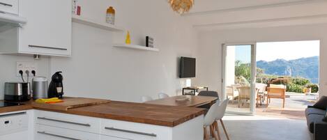 Una cocina moderna con armarios blancos, una encimera de madera y un comedor con mesa y sillas.
