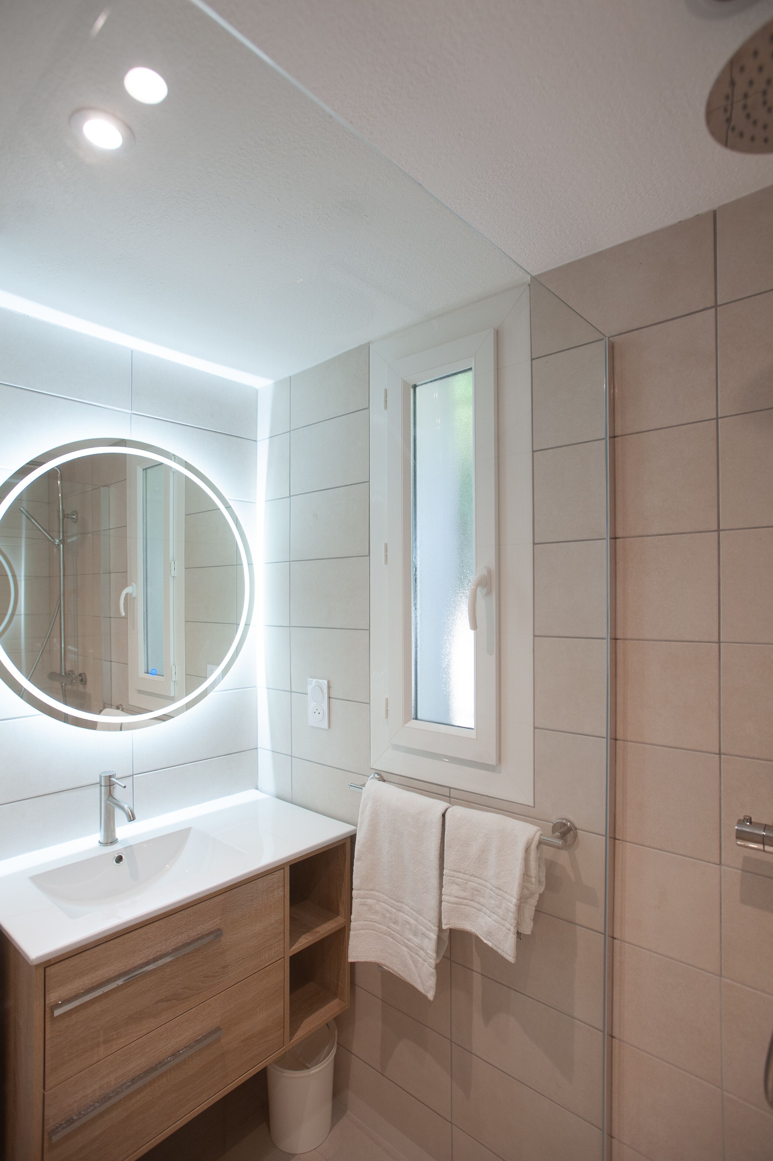 Un bagno moderno con uno specchio rotondo, un lavandino e una doccia.