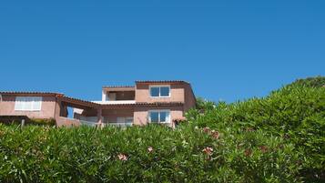 A two-story house with a flat roof and a balcony.