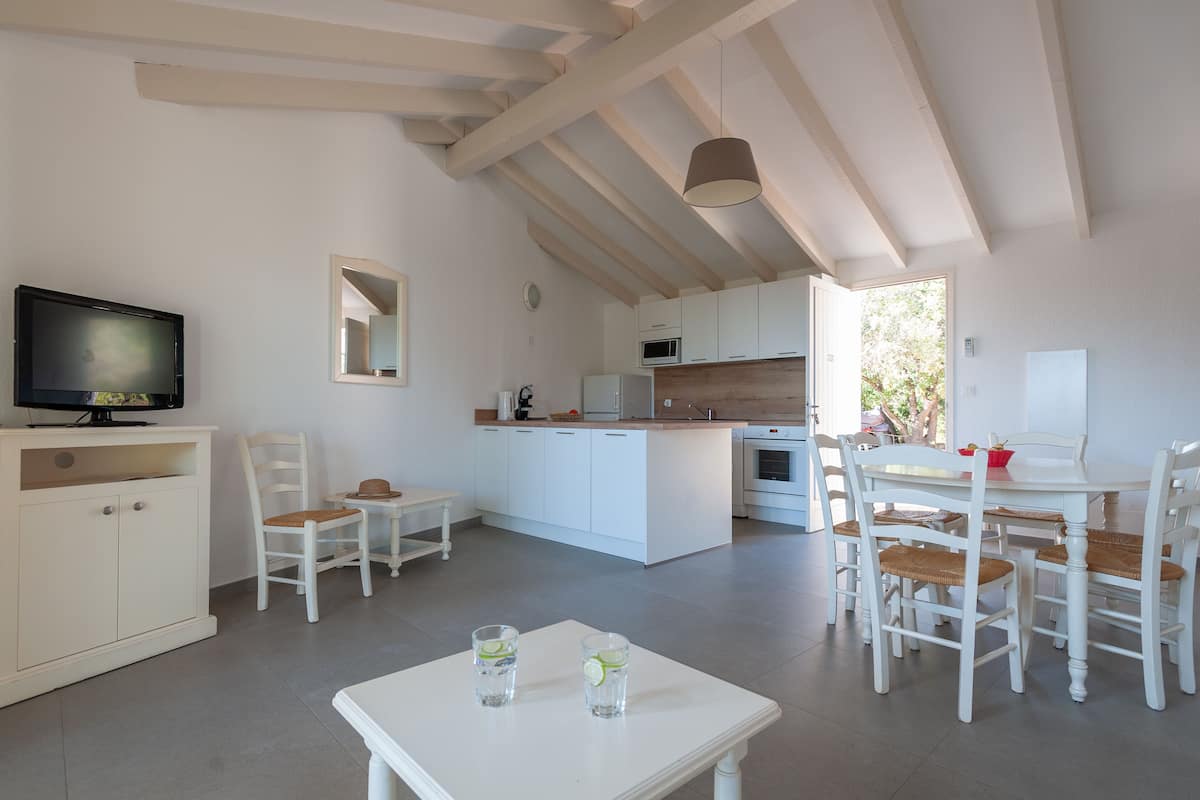 A modern kitchen with white cabinetry, a central island, and a dining area with white chairs and a table.
