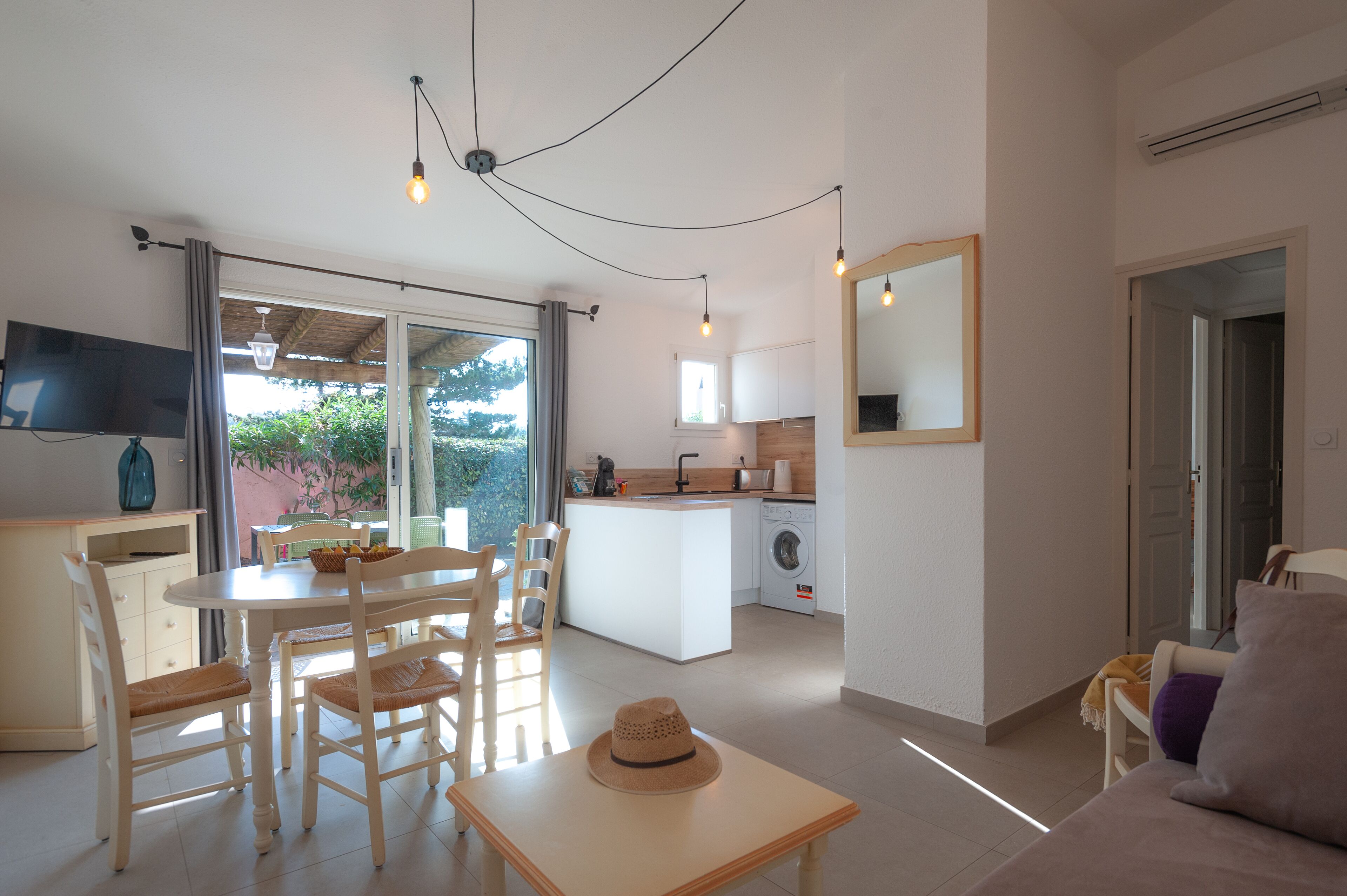 A modern kitchen with a central island, a dining area with a table and chairs, and a living area with a sofa and a TV.
