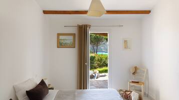 Un dormitorio con una cama, una silla, una maleta y vistas al exterior.