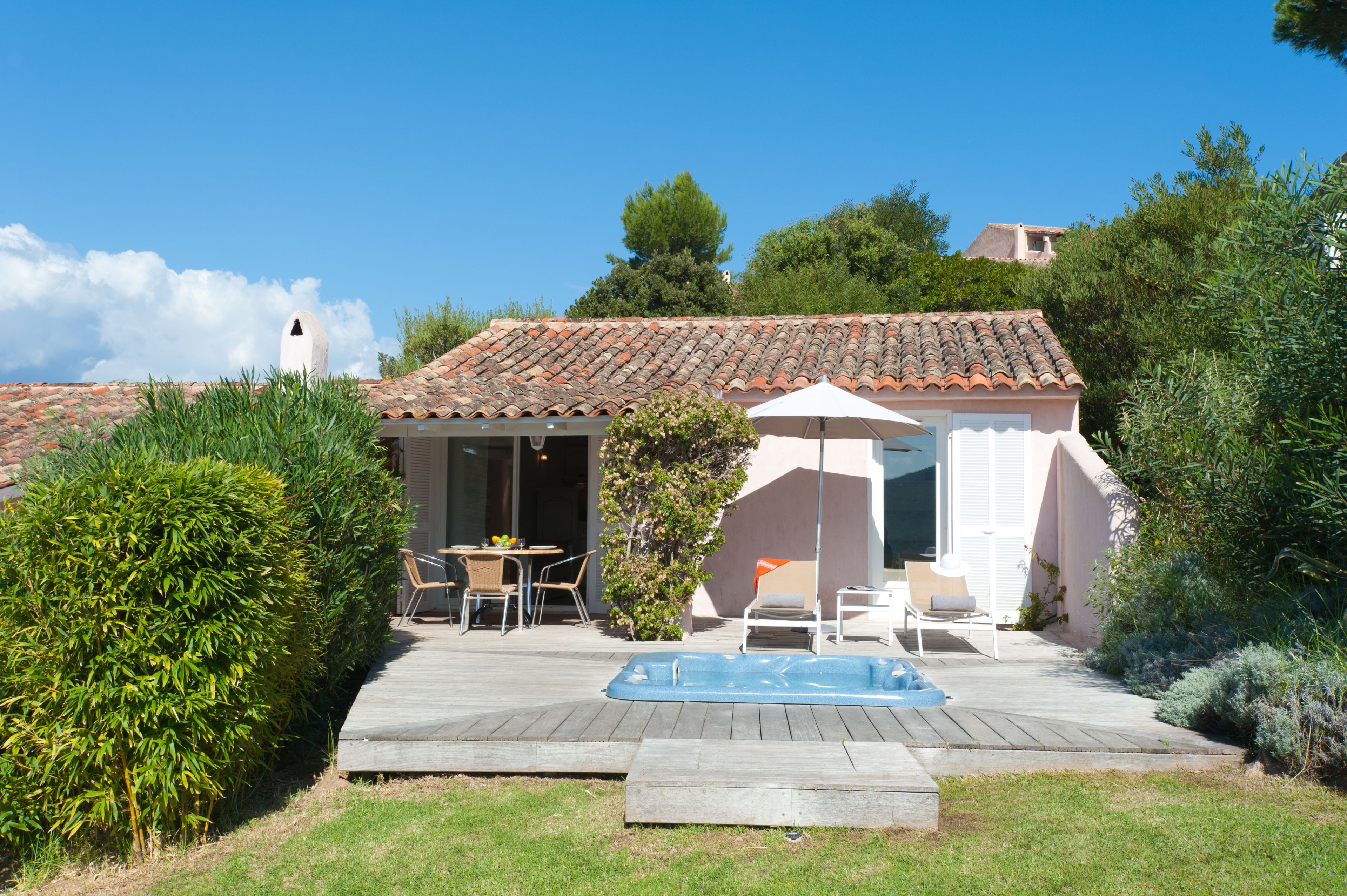 A house with a tiled roof, a swimming pool, and a patio area with outdoor furniture.