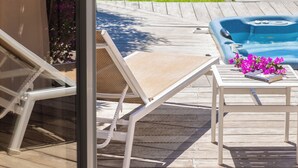 Terraza con sillones de descanso, jacuzzi y vista a un paisaje montañoso.