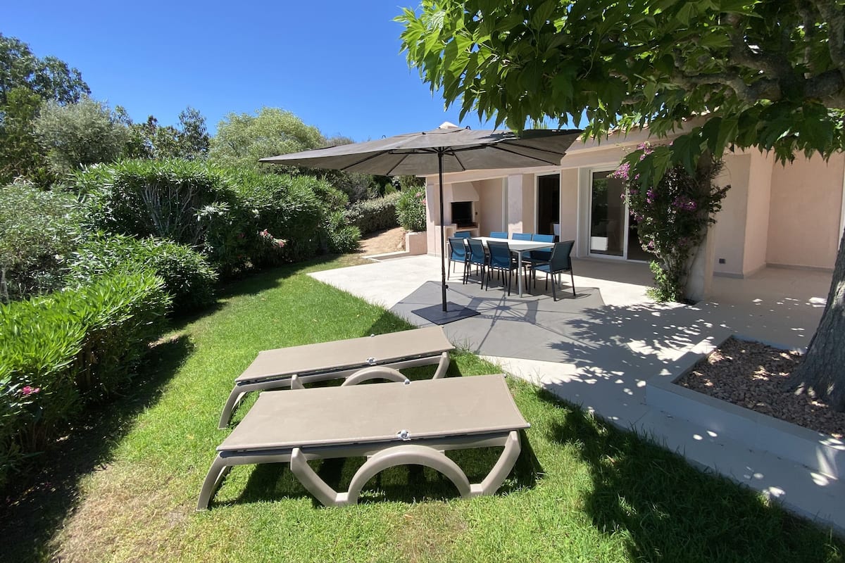 A patio with a table and chairs, a covered seating area, and a well-maintained lawn.