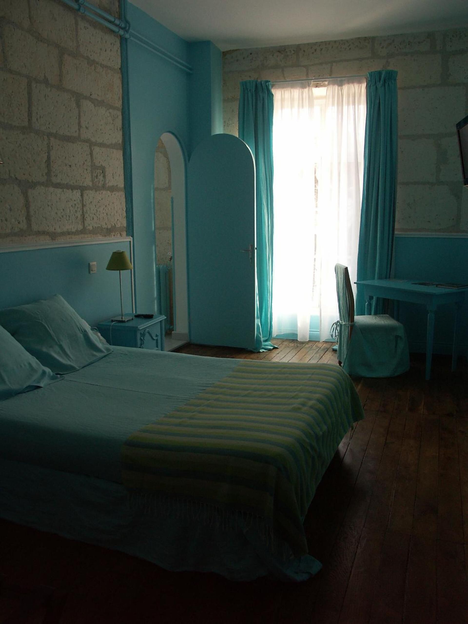 A bedroom with a bed, a desk, and a chair.