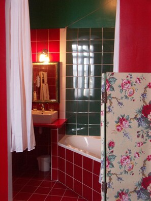 A bathroom with a red sink, a mirror, and a bathtub.