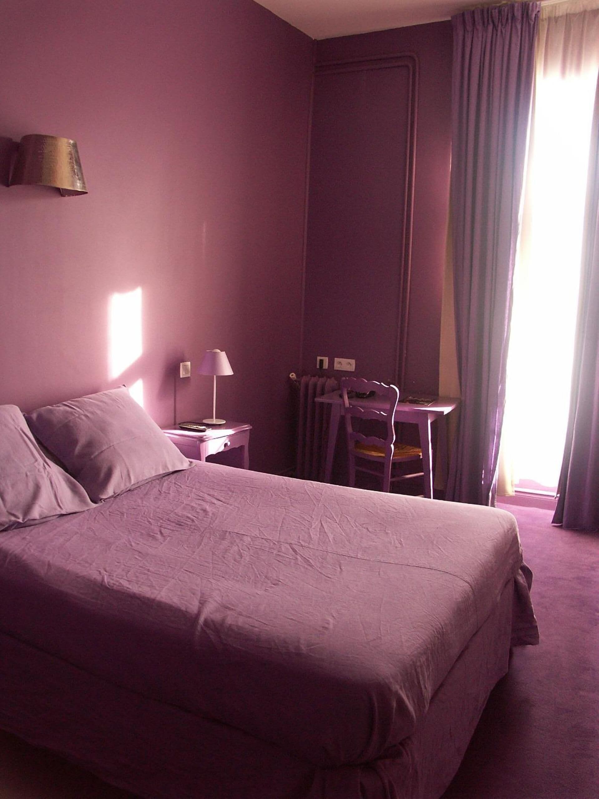 A room with a large bed, a desk, and a chair.